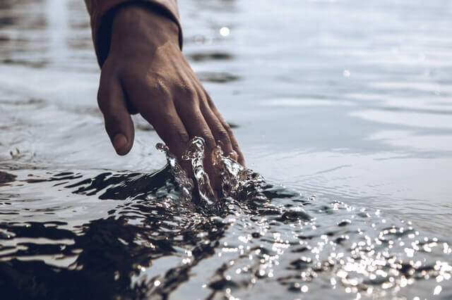 close-up-photo-of-a-person-s-hand-touching-body-of-water-image